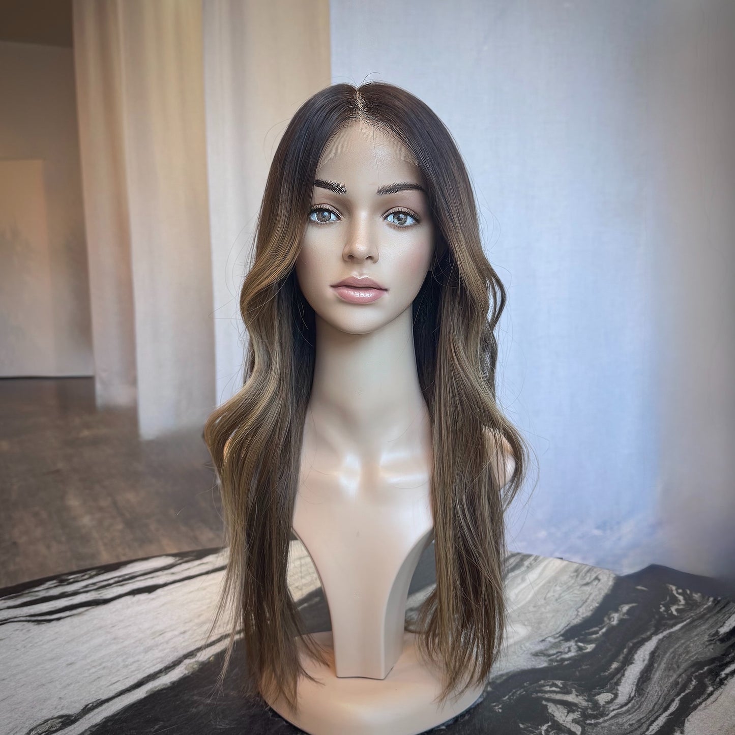 Mannequin head with a long brown ombre highlight wig on a marble surface