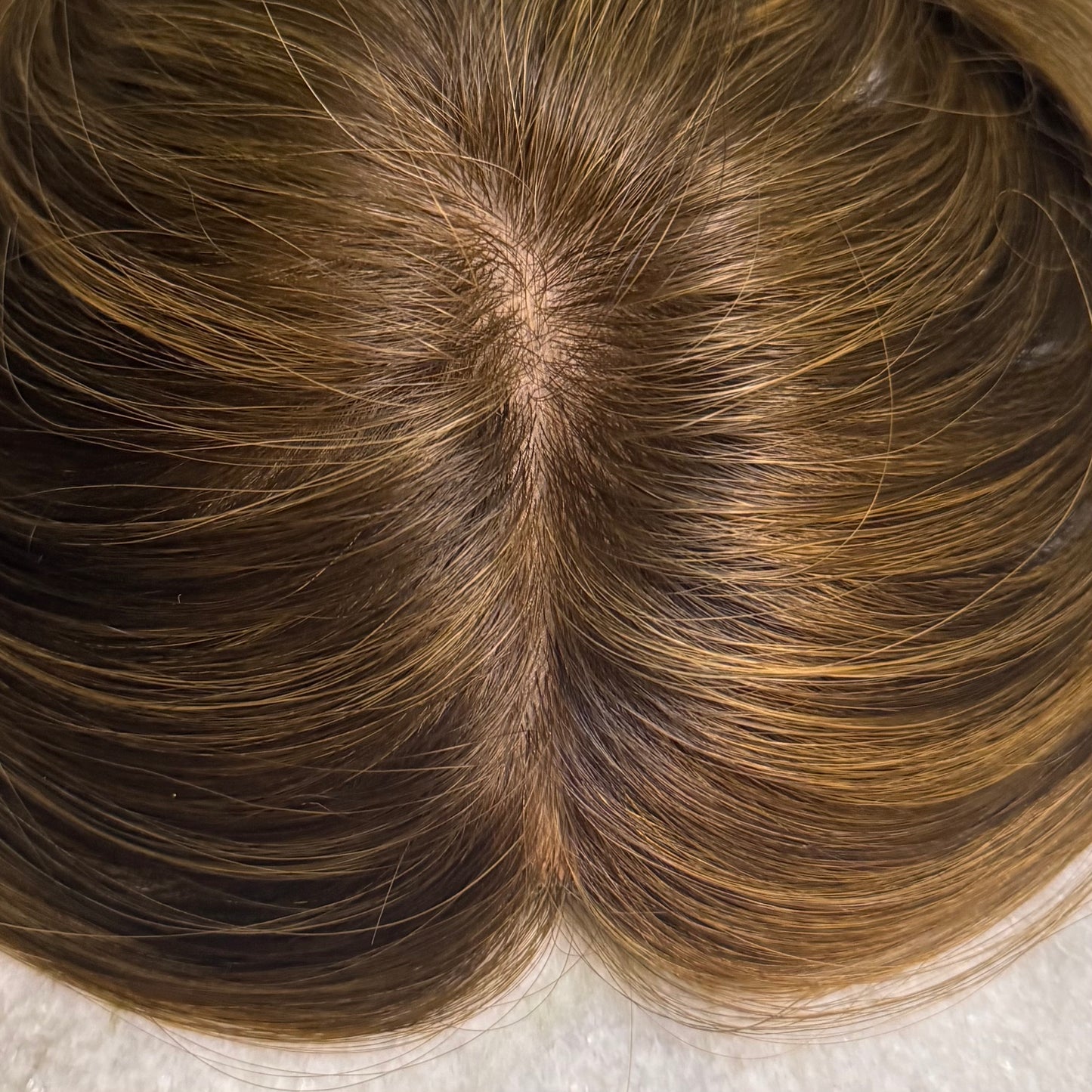 Close-up of the realistic Skin Top Hair Topper in Chestnut Brown with soft honey highlights, featuring a natural-looking scalp and seamless part line.